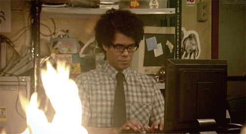 Scène de la série de The IT Crowd. On y voit un développeur concentrer sur son ordi et le feu qui brule sur son bureau